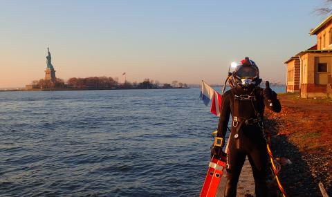Jacobs engineer diver poses in front of NYC waterfront with Statue of Liberty in the background