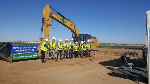 Groundbreaking ceremony with team in neon yellow PPE in front of a bulldozer