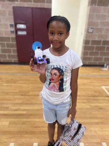 Young black girl displays her white race car