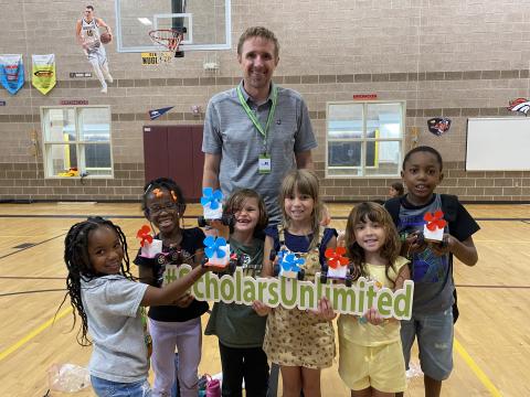 Group of kids and one male volunteer hold Scholars United sign