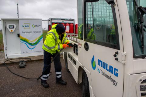 Man refueling luggage tractor at airport.