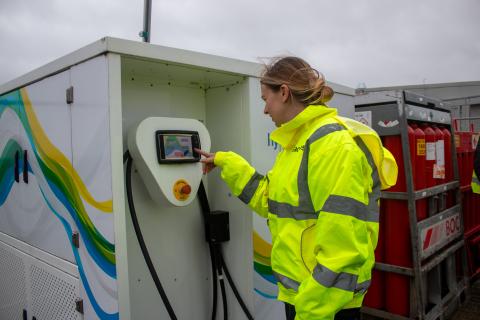 Woman with blonde hair wearing hi vis jacket programming refueler.