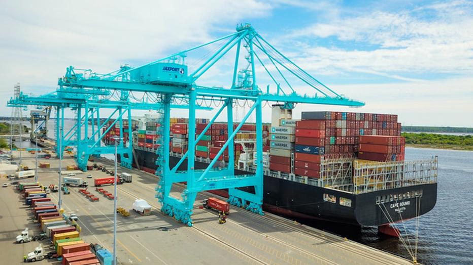 Container ship at a port with electric blue cranes