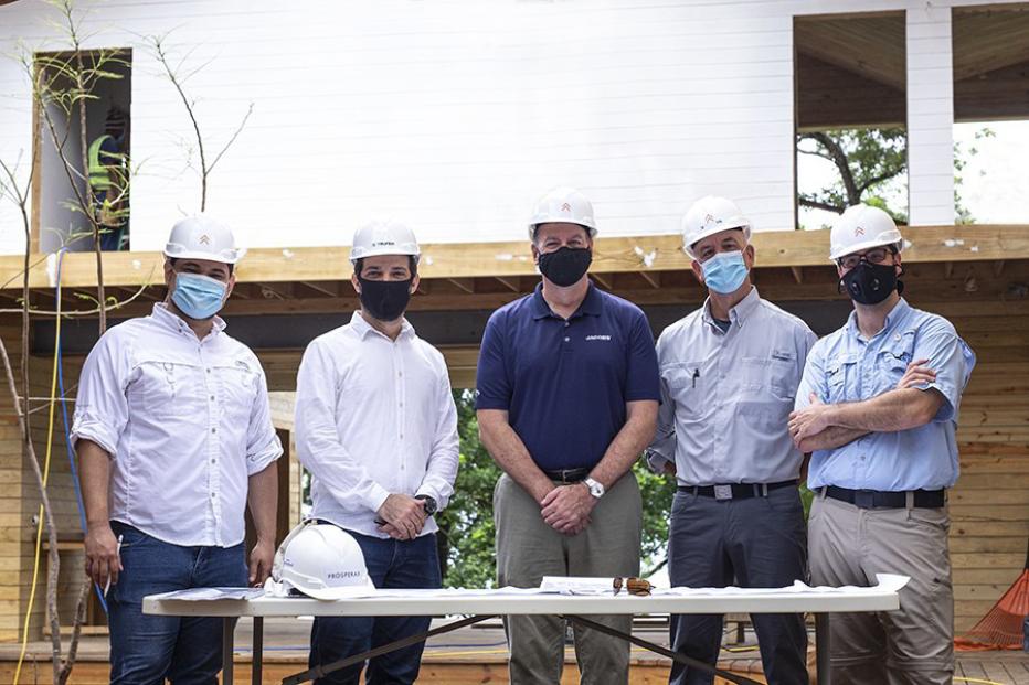 Five men in hard hats and masks standing on a construction site