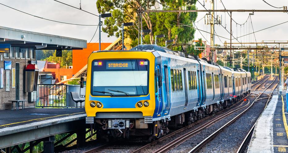Yellow and blue train on tracks rolling into a station