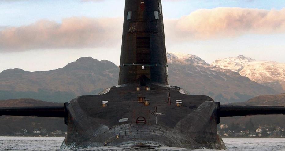 Submarine above water in front of mountains.