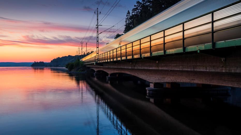 Railway bridge over water with a reflection of a colorful sunset in the water