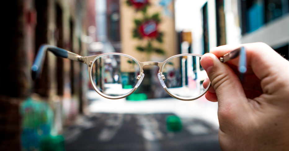 Streetscape out of focus with glasses in foreground helping focus