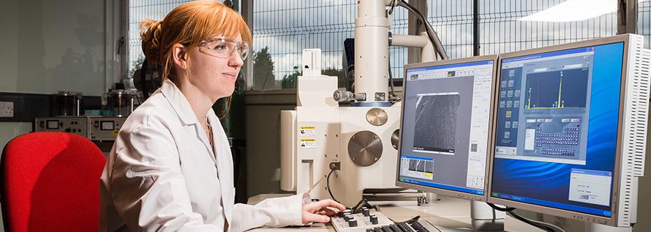 Red haired woman in a white lab coat at a computer