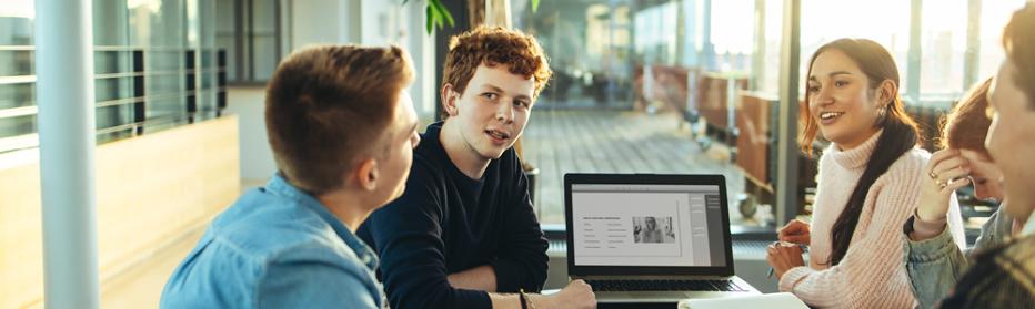 young adults around a table with a laptop