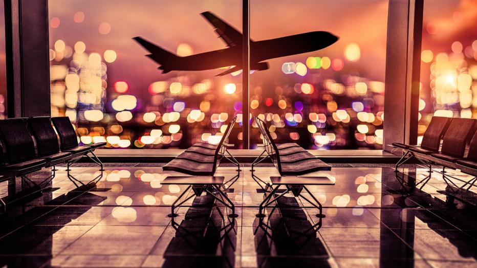 View from inside airport terminal of airplane taking off at night