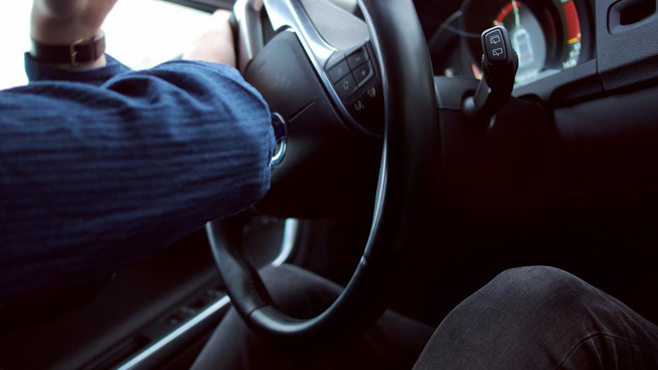 close up of steering wheel with distracted driver