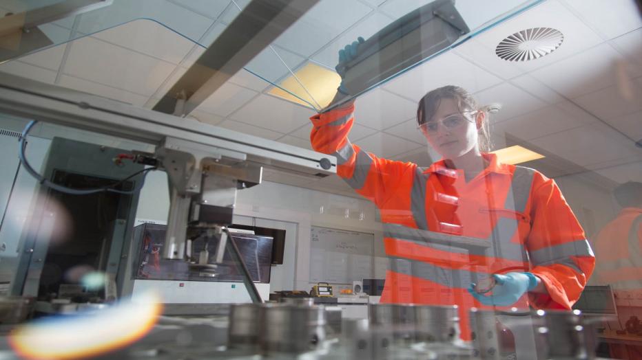 Brunette woman in orange PPE in a lab