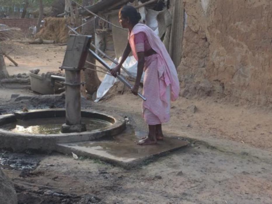 Woman pumping water from a well in India