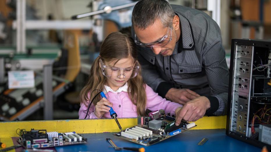 Man helping girl with STEAM activity with electronic board