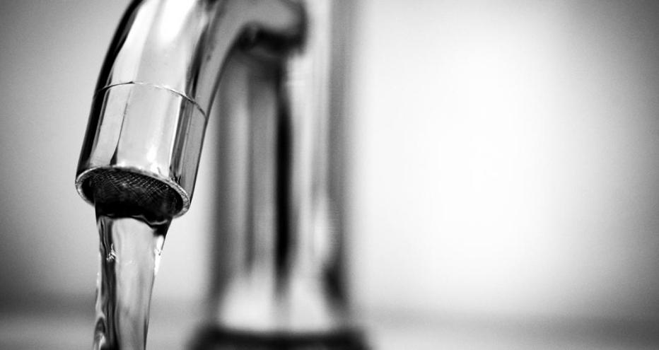 Stock image of a silver faucet with water flowing out