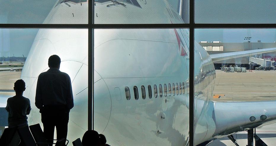 Two people looking at Delta airplane through terminal window