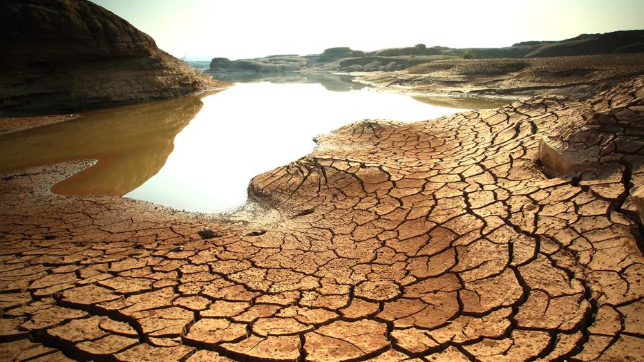 Dried and cracked land with pool of water rescinding