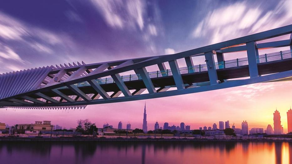 Dubai Water Canal up close - pink and purple hues with city scape and bridge