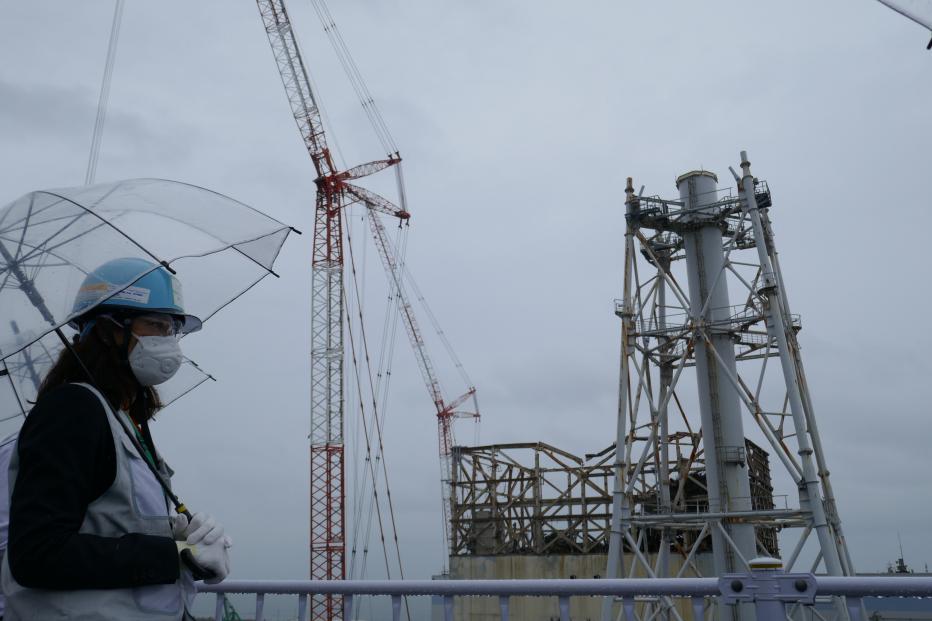 Teammate at Fukushima with an umbrella, PPE and face mask