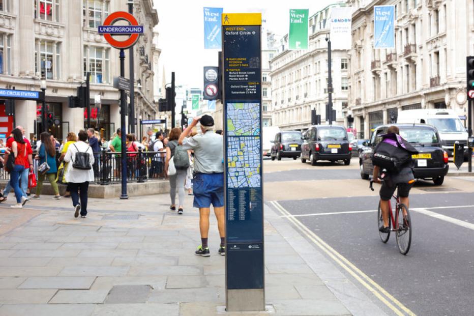 Entrance to Oxford Street London Underground station. Street with people walking, cyclists, taxis and other traffic