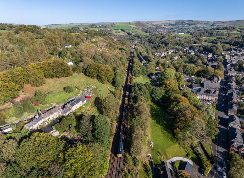 Aerial view of goods train, railway, fields and housing.