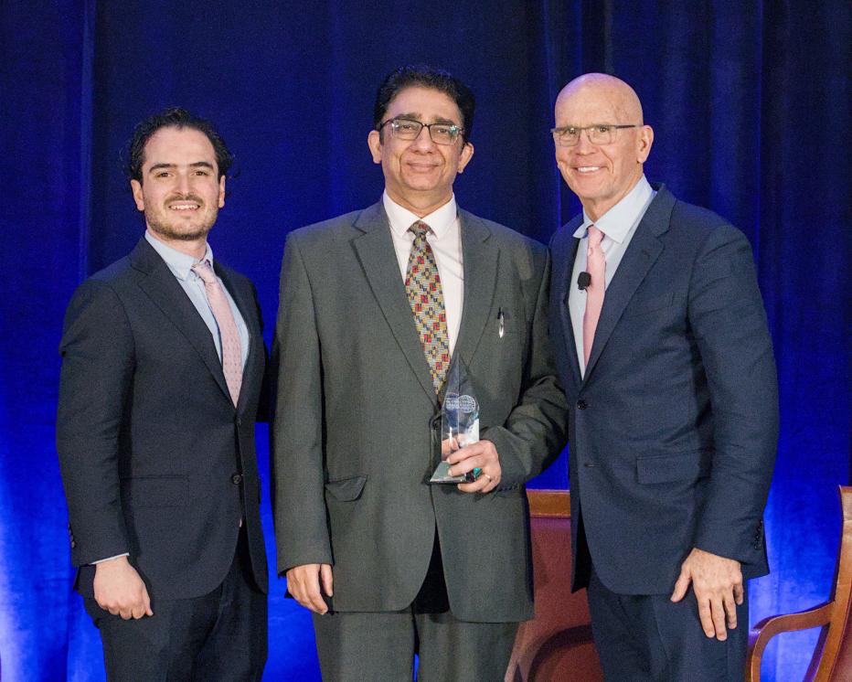 Raj Badhwar collecting an award from two other people
