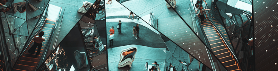 Abstract mirrored ceiling reflecting escalators, stairs, and people in a kaleidoscopic pattern