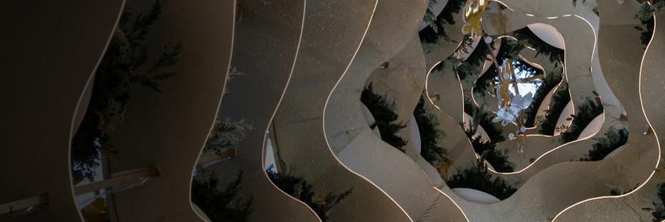 Spiral mirrored structure reflecting greenery and decorative elements inside