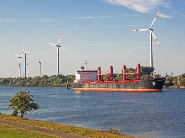 Empty freighter on river Weser with wind power plants onshore