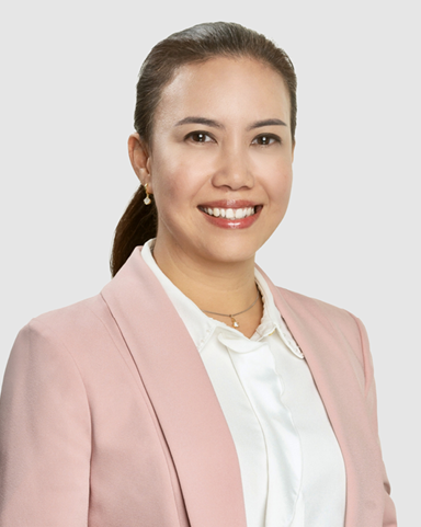Head‑and‑shoulders studio portrait of a person in a light pink blazer over a white collared shirt, photographed against a plain light gray background.