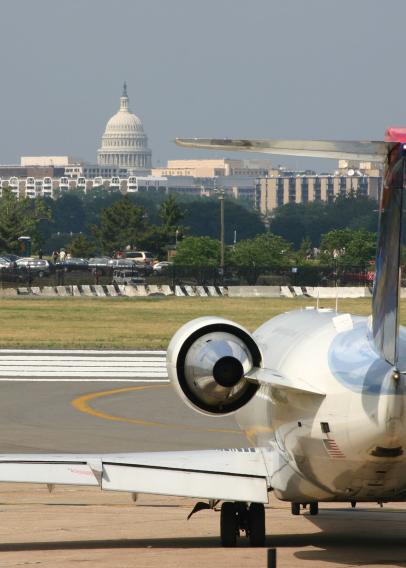 Airplane landing on a runway with Washington, DC skyline, including White House, in background