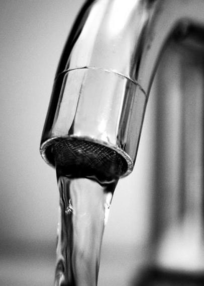Stock image of a silver faucet with water flowing out