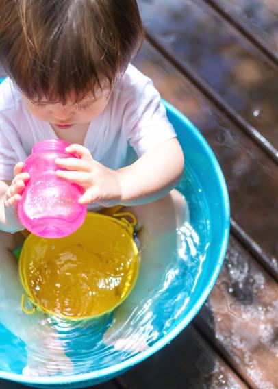 Toddler in a kiddie pool drinking out of a pink sippy cup