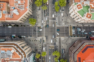 Aerial of a city street with cars, pedestrians, trees and brick buildings